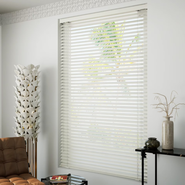 Living room with white blinds and brown couch, illuminated by natural light. Aluminum Venetian Blinds.