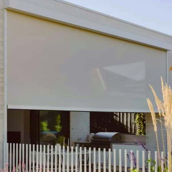 A white picket fence with a large white motorized shade and outdoor blinds.