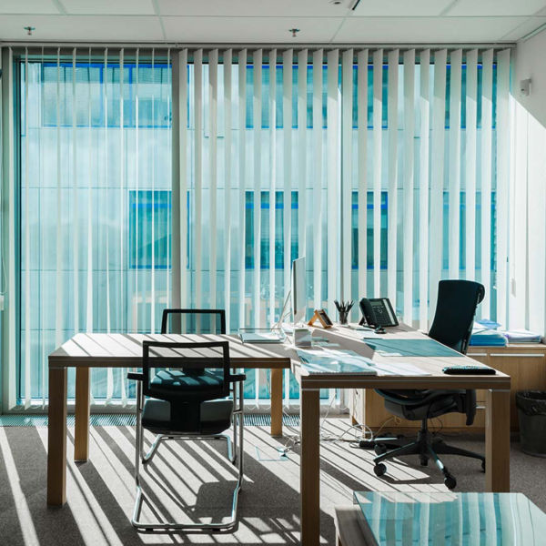 Interior of office with large windows, desk, and Vertical Blinds.