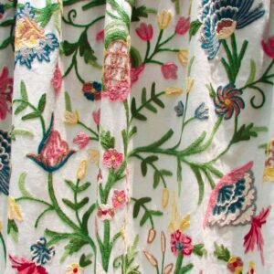 White curtain with colorful embroidered flowers, adding a touch of elegance to the room decor.