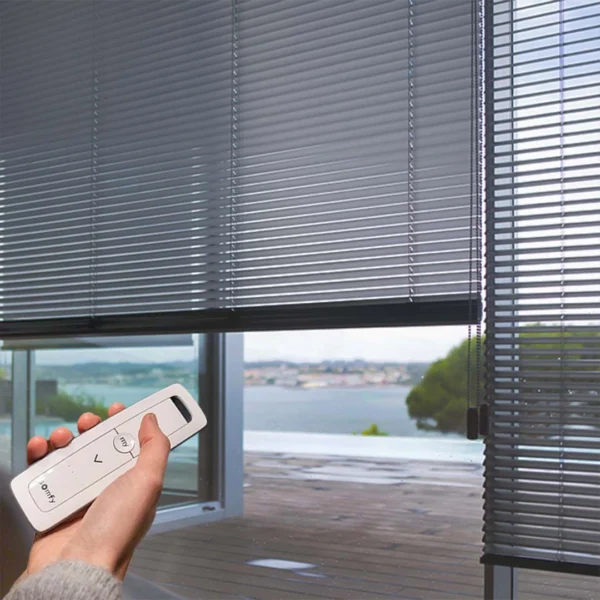 hand holding a remote facing the smart motorized aluminum blinds